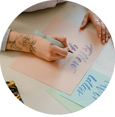 A person with a rose tattoo using a waterbrush to paint words